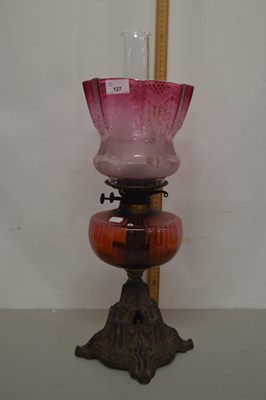 Lot 127 - Cranberry glass oil lamp with cast iron base...