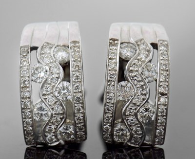 Lot 300 - A pair of 18ct diamond earrings, the curved...