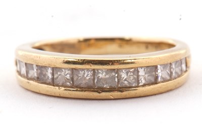 Lot 24 - A diamond ring, the channel set graduated...