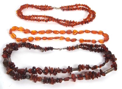 Lot 207 - Three amber bead necklaces: one with irregular...