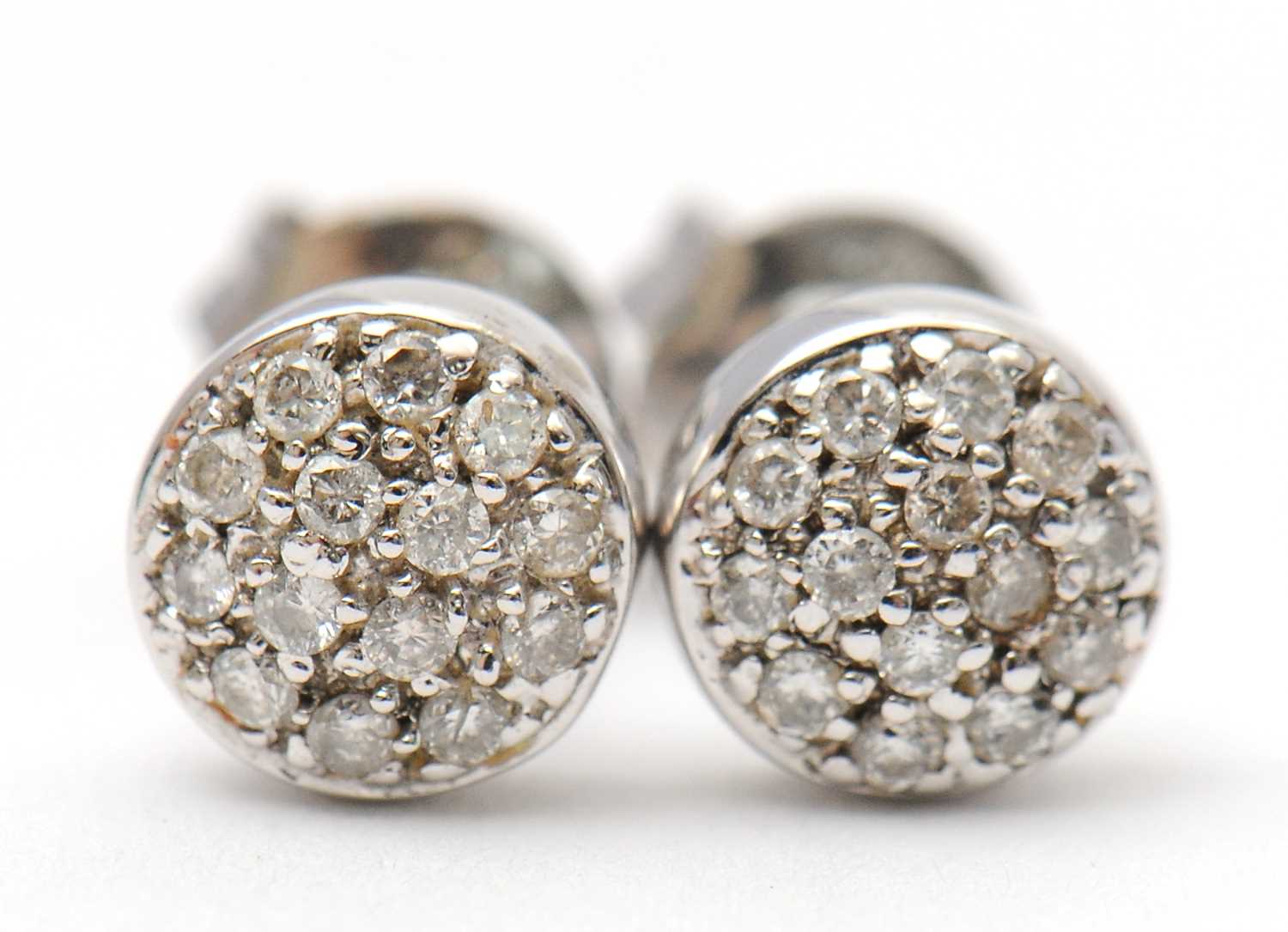 Lot 42 - A pair of diamond earrings, the slightly domed...