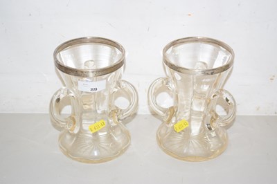 Lot 89 - A pair of clear glass tyg vases with silver...