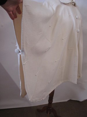 Lot 80 - A cream cotton cape by Lydia G, with button...