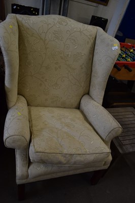 Lot 870 - A beige upholstered wing back armchair